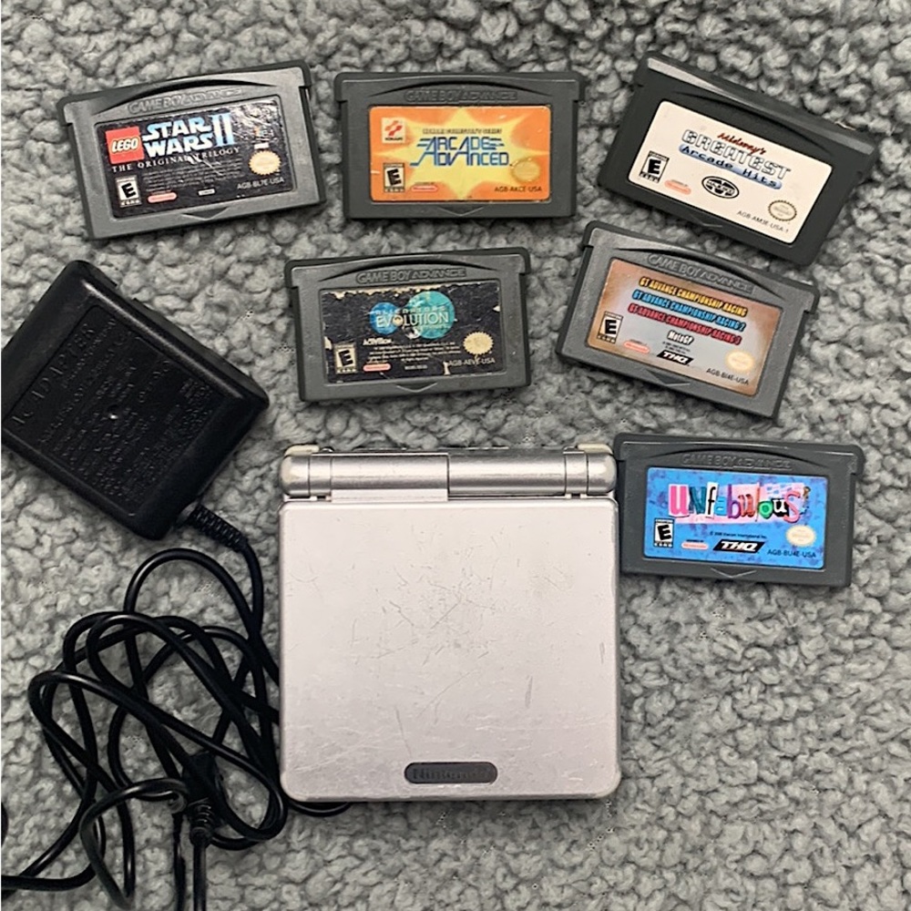 Silver Nintendo Gameboy with charger and six games included.